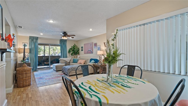 dining room with a textured ceiling, light hardwood / wood-style floors, and ceiling fan