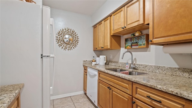 kitchen featuring light tile patterned floors, white appliances, light stone counters, and sink