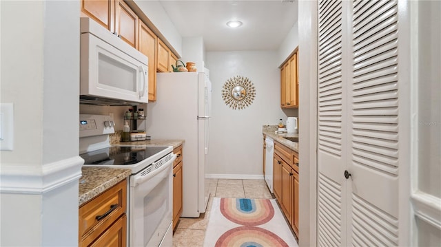 kitchen with light stone counters, light tile patterned floors, and white appliances