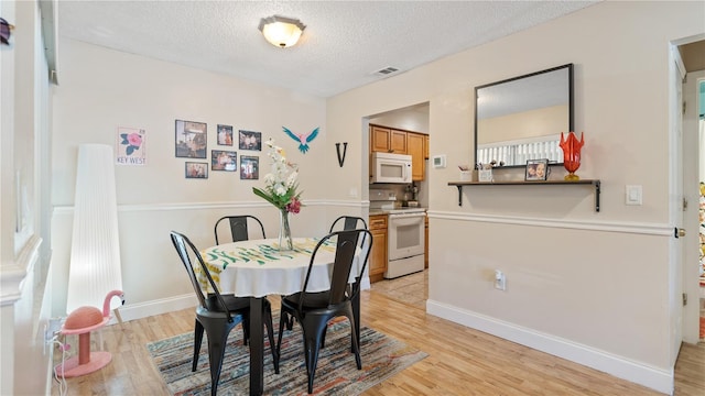 dining space featuring light hardwood / wood-style floors and a textured ceiling