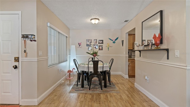 dining room with light hardwood / wood-style floors and a textured ceiling