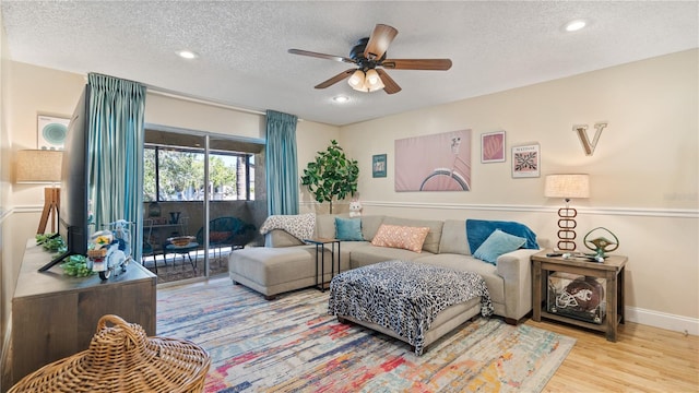 living room with ceiling fan, light hardwood / wood-style flooring, and a textured ceiling