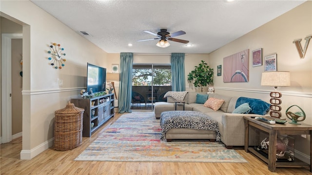 living room featuring ceiling fan, a textured ceiling, and hardwood / wood-style flooring