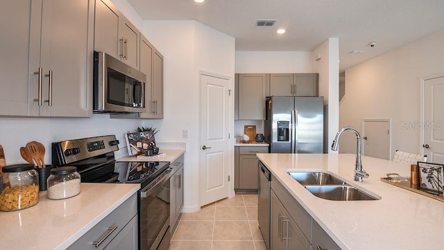 kitchen featuring light tile patterned flooring, appliances with stainless steel finishes, gray cabinets, and sink