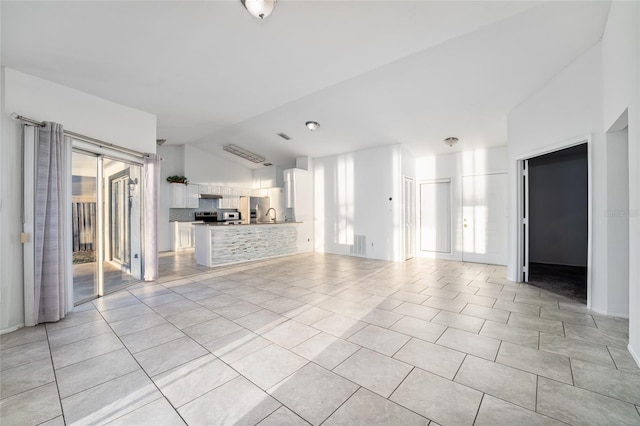 unfurnished living room with light tile patterned floors and vaulted ceiling