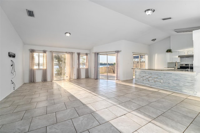 unfurnished living room featuring sink, vaulted ceiling, and light tile patterned flooring