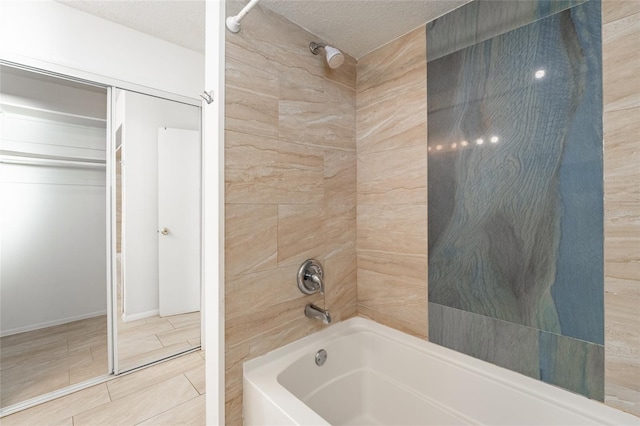 bathroom featuring a textured ceiling and tiled shower / bath combo