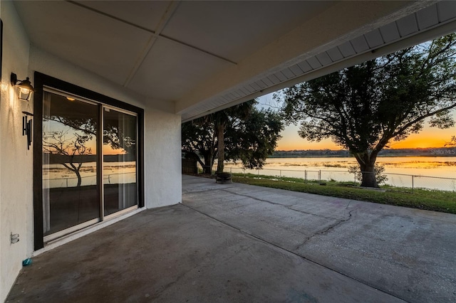 patio terrace at dusk featuring a water view