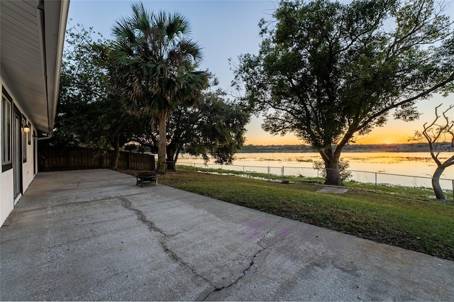 patio terrace at dusk with a water view and a lawn