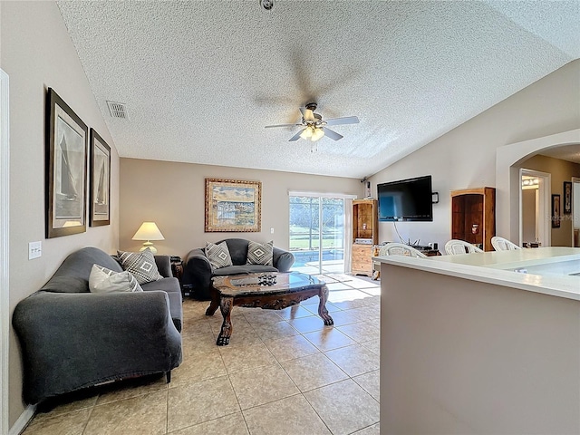 living room with ceiling fan, light tile patterned floors, a textured ceiling, and vaulted ceiling