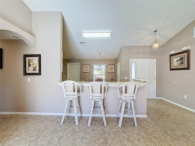 kitchen featuring a kitchen breakfast bar, a textured ceiling, light tile patterned floors, and hanging light fixtures