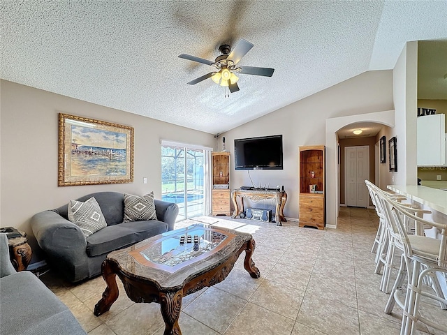 living room featuring a textured ceiling, ceiling fan, light tile patterned floors, and lofted ceiling