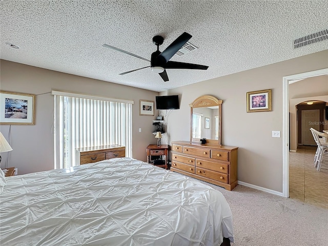 bedroom featuring a textured ceiling, light colored carpet, and ceiling fan