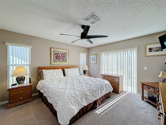 carpeted bedroom with multiple windows, a textured ceiling, and ceiling fan