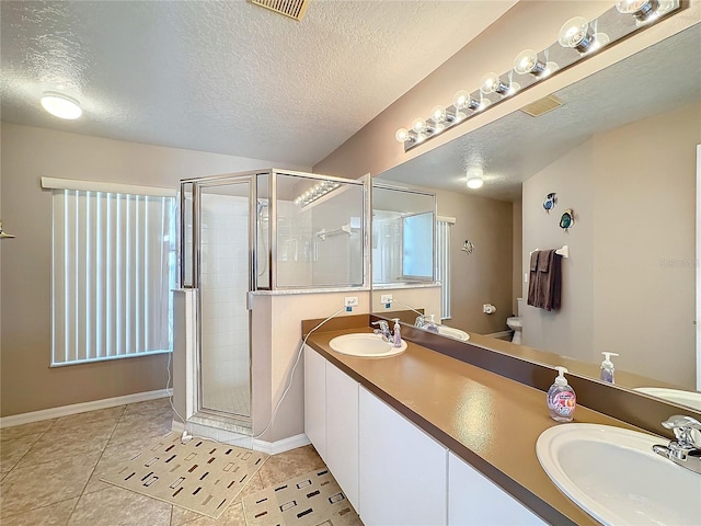 bathroom featuring tile patterned flooring, vanity, a shower with shower door, and a textured ceiling