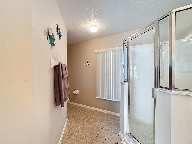 bathroom featuring tile patterned floors, an enclosed shower, and a textured ceiling