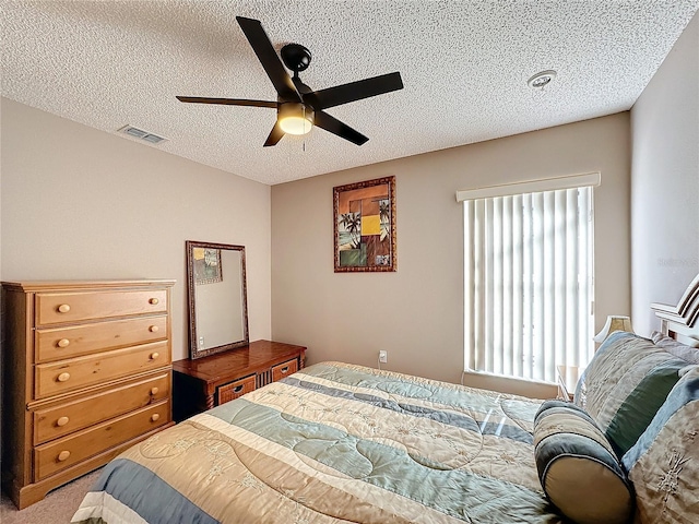 carpeted bedroom featuring ceiling fan and a textured ceiling