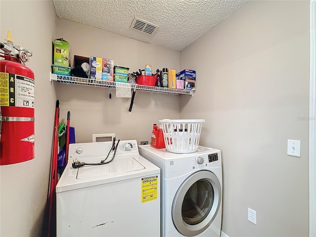 clothes washing area with a textured ceiling and separate washer and dryer