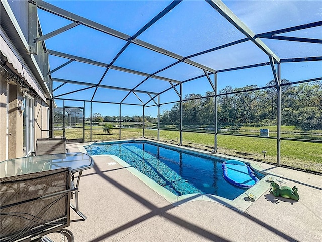 view of pool with a lawn, glass enclosure, and a patio