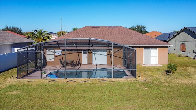 back of property with a fenced in pool, glass enclosure, a patio area, and a yard