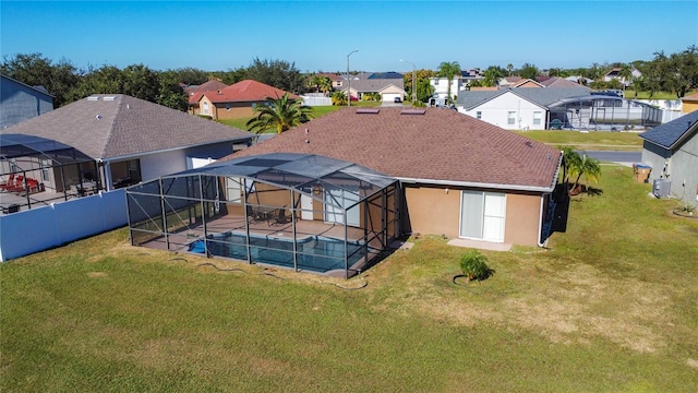 rear view of house with a lanai, a patio area, a lawn, and a fenced in pool