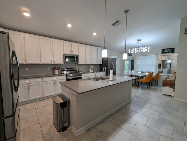 kitchen featuring appliances with stainless steel finishes, sink, decorative light fixtures, a center island with sink, and white cabinets