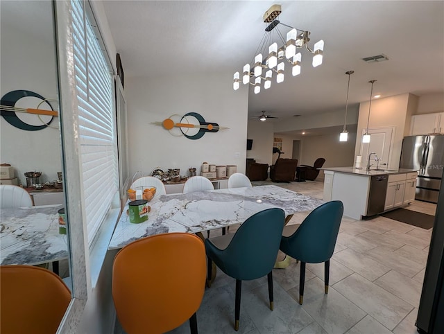 dining room with ceiling fan with notable chandelier and sink