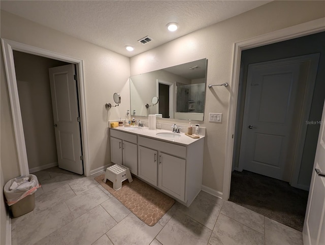 bathroom with a textured ceiling, vanity, tile patterned floors, and a shower with door