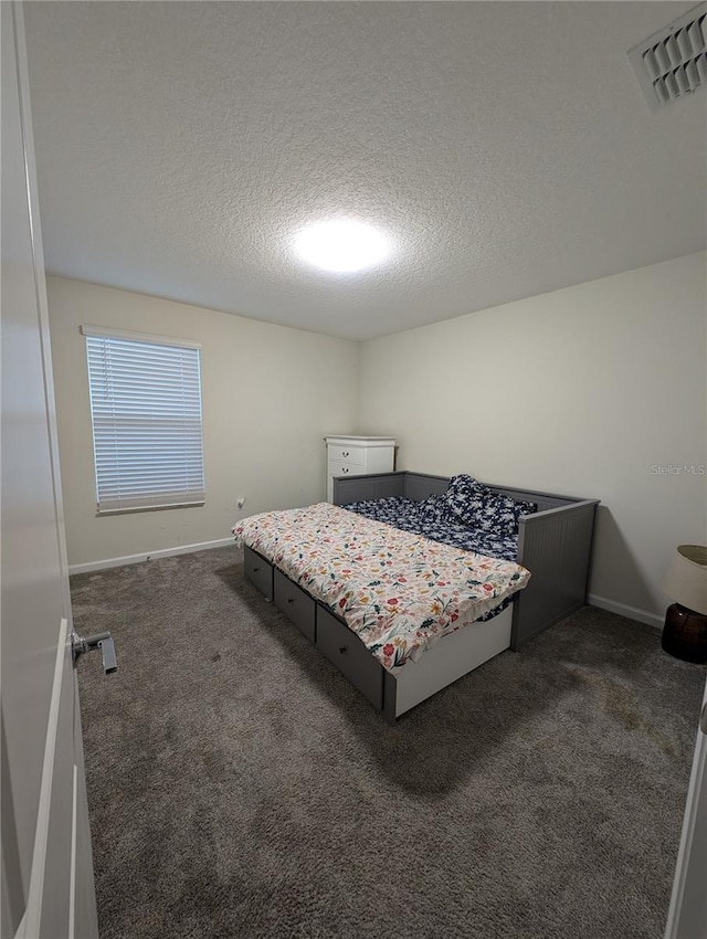 bedroom featuring dark colored carpet and a textured ceiling