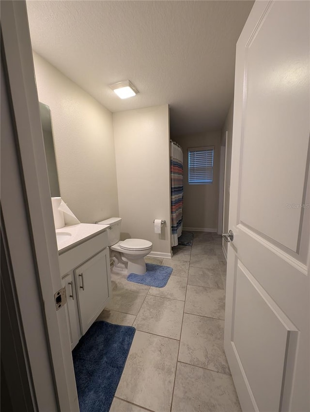 bathroom with a textured ceiling, vanity, and toilet