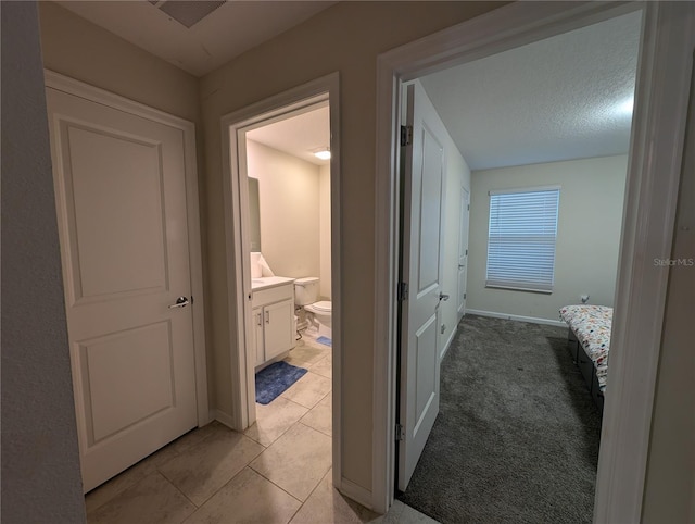 hall featuring a textured ceiling and light carpet