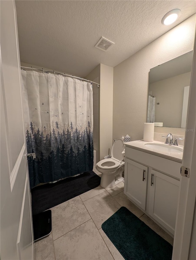 bathroom featuring tile patterned flooring, vanity, a textured ceiling, and toilet