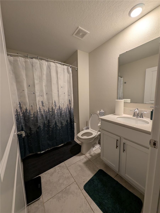 bathroom with tile patterned floors, vanity, a textured ceiling, and toilet