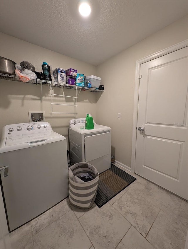 laundry area with washer and dryer, light tile patterned floors, and a textured ceiling