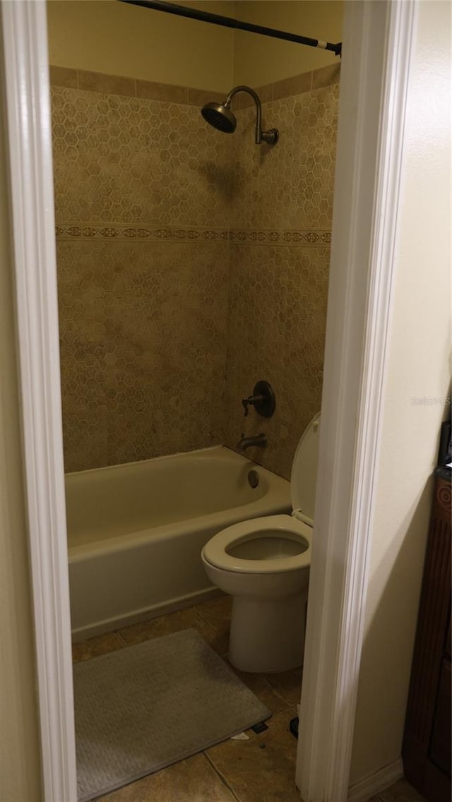 bathroom with tile patterned flooring, toilet, and tiled shower / bath