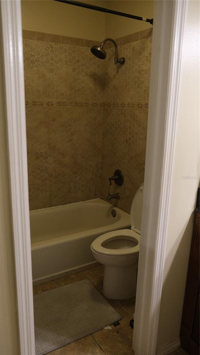 bathroom with tile patterned flooring, tiled shower / bath, and toilet