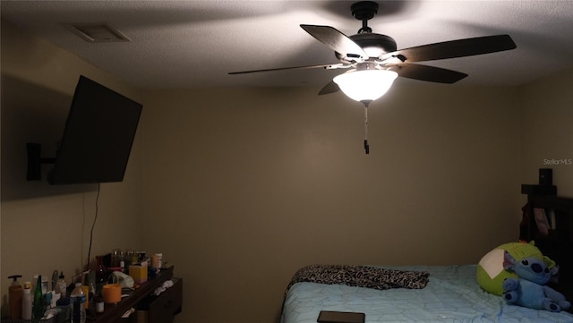 bedroom with ceiling fan and a textured ceiling