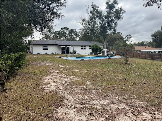 rear view of house featuring a fenced in pool and a lawn