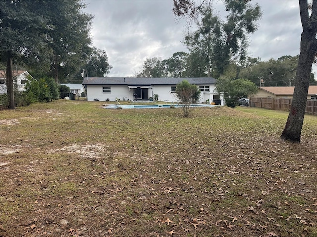 rear view of property featuring a yard and a fenced in pool