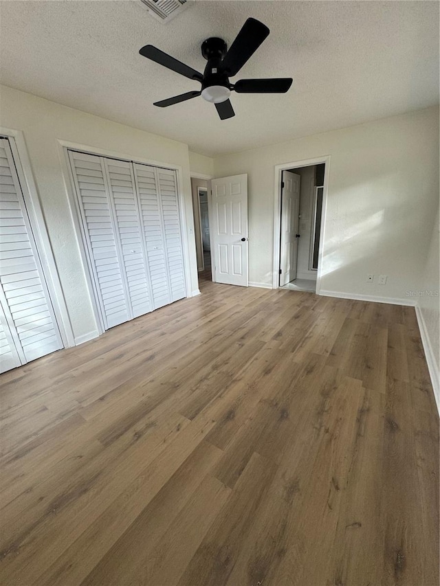 unfurnished bedroom with hardwood / wood-style flooring, ceiling fan, and a textured ceiling