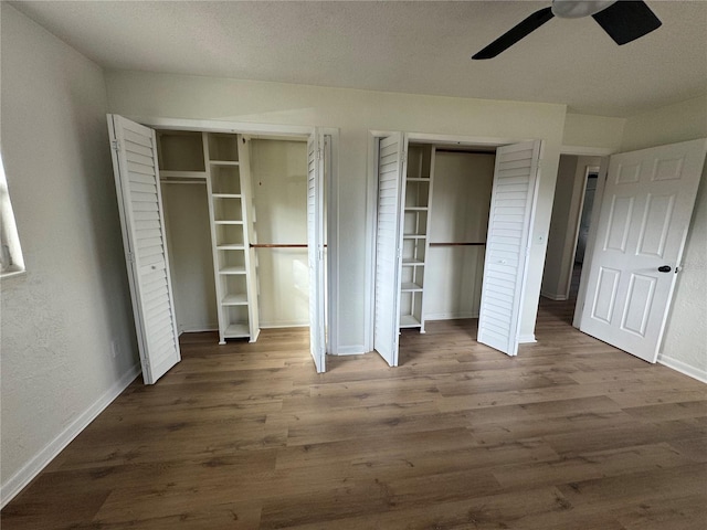 unfurnished bedroom with multiple closets, ceiling fan, and dark hardwood / wood-style floors