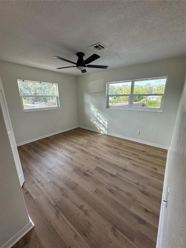 spare room with plenty of natural light, wood-type flooring, and a textured ceiling