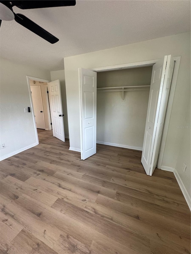 unfurnished bedroom featuring ceiling fan, a closet, and wood-type flooring