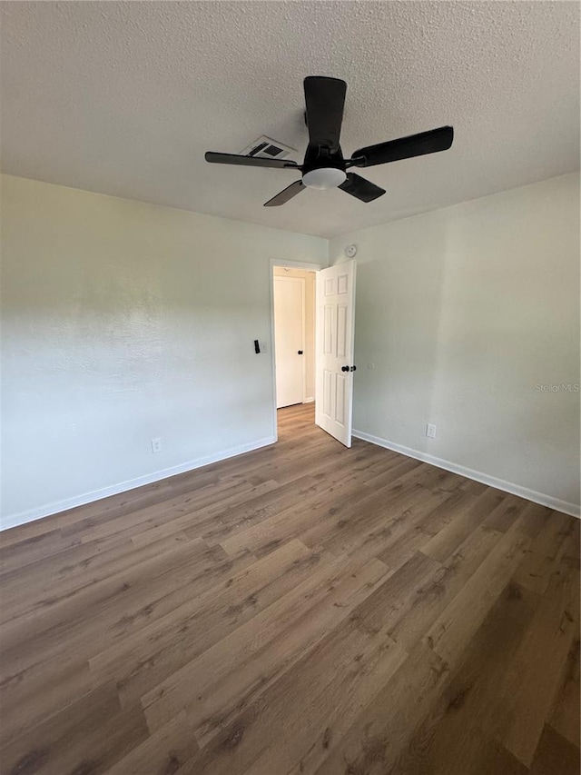 spare room featuring a textured ceiling, ceiling fan, and dark wood-type flooring