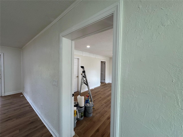 hall with a textured ceiling, dark hardwood / wood-style floors, and ornamental molding