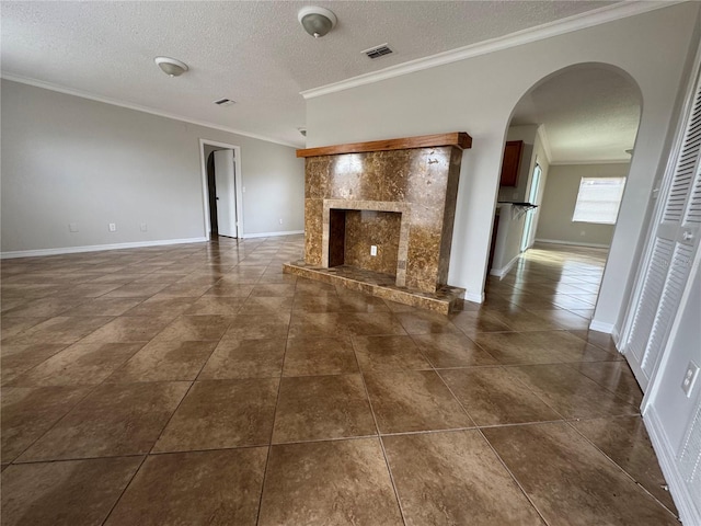 unfurnished living room featuring crown molding, a fireplace, dark tile patterned floors, and a textured ceiling