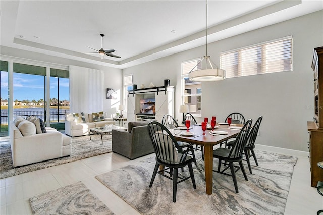 tiled dining space featuring ceiling fan and a tray ceiling