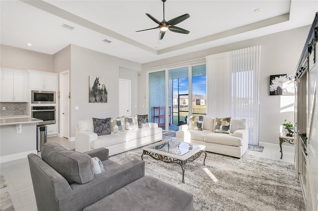 living room featuring a barn door, a raised ceiling, and ceiling fan