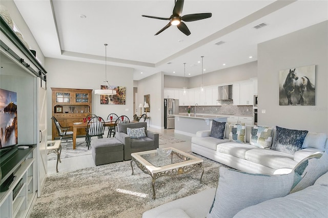 living room featuring a raised ceiling and ceiling fan