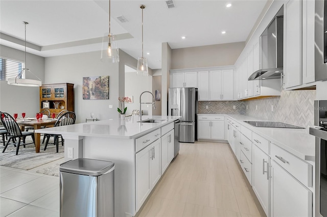 kitchen featuring white cabinets, stainless steel appliances, sink, and an island with sink